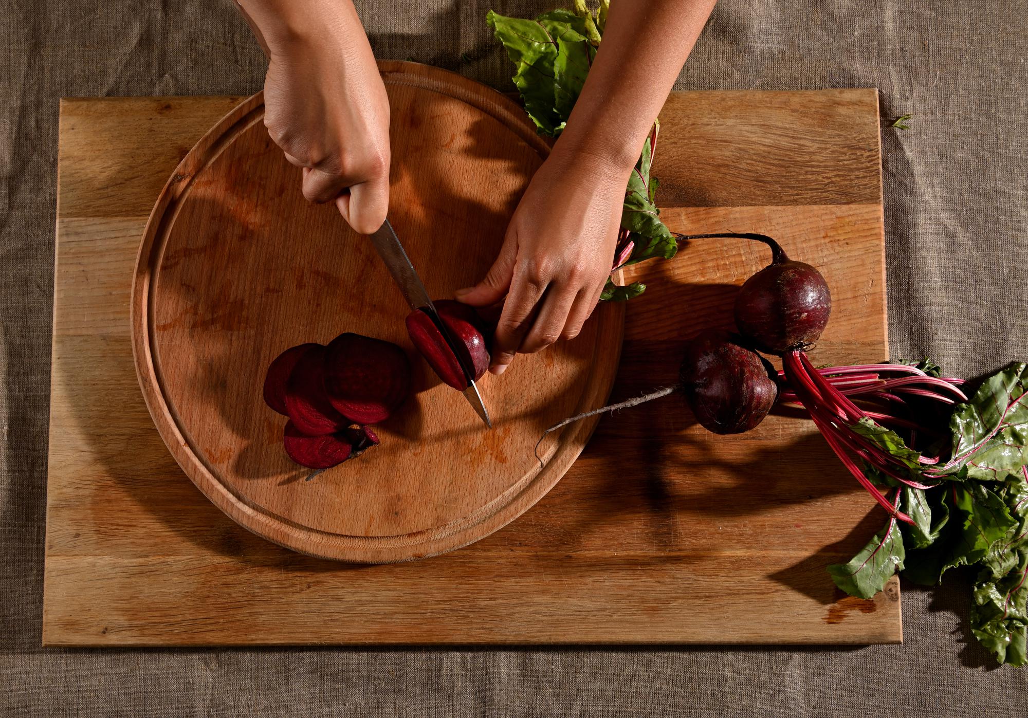 Hands chopping vegetables on wooden board
